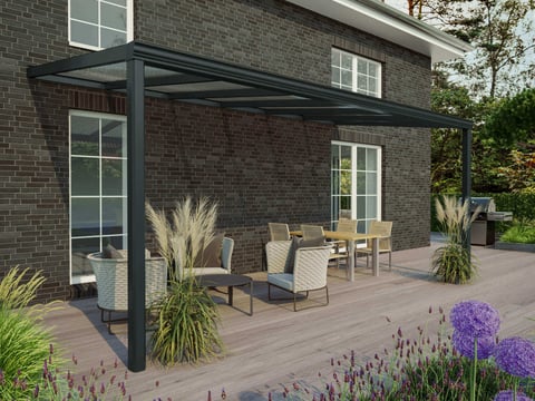 Anthrazitfarbene Terrassenüberdachung mit elegantem Design, umgeben von einer gemütlichen Sitzecke und grüner Gartenlandschaft