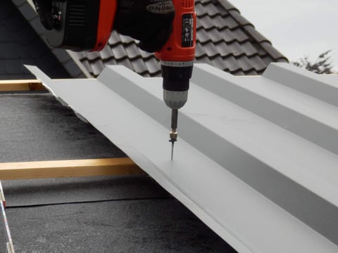Montage eines Stehfalzblechs auf dem Dach, Sicherung mittels Schraubendreher, optimale Befestigung für Langlebigkeit und Stabilität