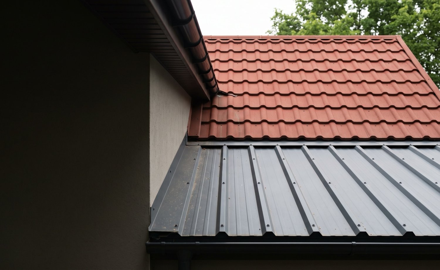 Ziegelrotes Pfannenblech auf dem Hausdach und anthrazitfarbenes Trapezblech auf dem Anbau