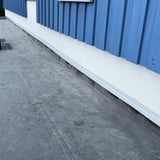Graues Dach Reparaturband an der Wand eines blauen Holzhauses verlegt