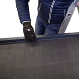 Montage des anthrazitgrauen Dachrandprofils CUBE auf einem Flachdach, Person auf Leiter
