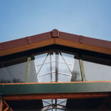 Endst

ck aus Faserzement in Rotbraun auf einem Dachgiebel mit Glasfront, blauer Himmel