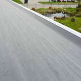 Verlegte schwarze EPDM Dachfolie auf einem Flachdach mit weißer Attika, Blick über das Dach