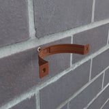 Kupferbraune Fallrohrschelle aus Stahl, Polyurethan beschichtet, an einer Ziegelwand montiert