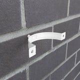Einzelne reinweiße Fallrohrschelle aus Stahl an einer dunklen Ziegelwand