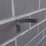 Einzelne anthrazitgraue Fallrohrschelle aus Stahl, 50 µm Polyurethan beschichtet, an einer Ziegelwand montiert