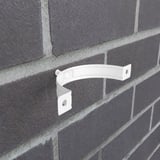 Reinweiße Fallrohrschelle aus Stahl an einer dunklen Ziegelwand montiert