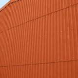 Wandverkleidung aus ziegelroten Faserzement Wellplatten Europa Profil 5, vertikal montiert