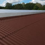Dachfläche mit rotbraunen Faserzement Wellplatten Europa Profil 5 und heller Firstabdeckung