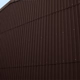 Fassade verkleidet mit dunkelbraunen Faserzement Wellplatten Europa Profil 5, vertikal montiert