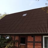 Dach eines Fachwerkhauses mit dunkelbraunen Faserzement Wellplatten Europa Profil 5 und einem Lichtelement