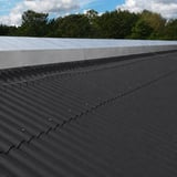 Dachfläche aus anthrazitschwarzen Faserzement Wellplatten Europa Profil 6, mit sichtbaren Befestigungsschrauben