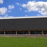Stallgebäude mit anthrazitschwarzem Dach aus Faserzement Wellplatten Europa Profil 6 und darunter liegenden Tieren