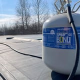 Flächenkleber Spraybond 100 Behälter mit blauem DACHPROTECT Etikett auf Dachbahn, Verlegung