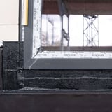 Fensterrahmen mit schwarzem Flüssigkunststoff abgedichtet, Detailansicht der Abdichtung