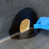 Hand mit blauem Handschuh streicht Kleber um ausgeschnittenes Loch fuer Seitenablauf