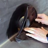 Haende setzen schwarzen Garantie-Seitenablauf in vorbereitetes Loch auf EPDM-Bahn ein