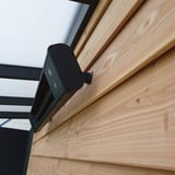 Schwarze Aluminium-Heizung an Holzwand, seitliche Ansicht mit Halterung, unter transparentem Dach