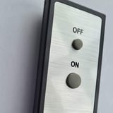 Detailansicht der Fernbedienung mit 'ON' und 'OFF' Tasten, gebürstete Metalloberfläche