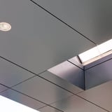Deckenverkleidung mit quadratischen Platten und integrierten Leuchten, eine Öffnung für Tageslicht