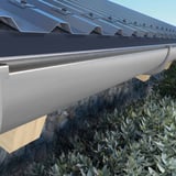 Graue PVC-Dachrinne mit Konsolrinnenhaltern an einem Dach mit dunklen Trapezblechen