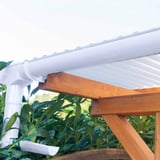 Weiße PVC-Dachrinne mit Fallrohr und Konsolrinnenhaltern an einer Holzkonstruktion