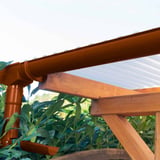 Braune PVC Dachrinne mit Fallrohr an einer Holzkonstruktion mit Lichtplatten