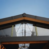 Ortgangwinkel in Anthrazitschwarz auf einem Dachfirst montiert, Holzkonstruktion und Glasfenster sichtbar
