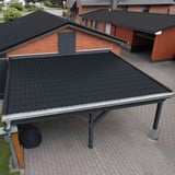 Pfannenblech Tiefschwarz RAL 9005 auf dem Dach eines Carports vor einem roten Backsteinhaus