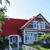 Pfannenblech 2/1060 weinrot auf einem Wohnhaus mit Ziegelmauerwerk, Verlegung am Dach