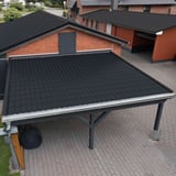Pfannenblech Tiefschwarz auf dem Dach eines Carports vor einem roten Backsteinhaus