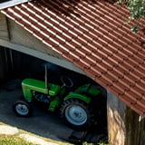 Pfannenblech EUROPA rotbraun auf einem Scheunendach, darunter ein grüner Traktor, Anwendungsbeispiel