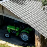 Pfannenblech EUROPA Weißaluminium auf einem Carport-Dach, darunter ein grüner Traktor