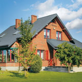 Ziegelhaus mit Dach aus Pfannenblech Szafir 350/15 in Fehgrau RAL 7000