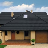 Pfannenblech Szafir 350/15 anthrazitgrau auf einem beigen Wohnhaus mit Gaube und Dachfenster
