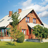 Rotes Backsteinhaus mit Dach aus Pfannenblech Szafir 350/15 in Reinweiß RAL 9010