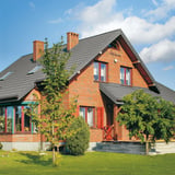 Ziegelrotes Haus mit Dach aus Pfannenblech Szafir 350/15 in Graualuminium RAL 9007