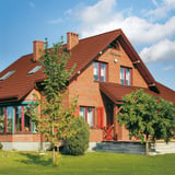 Ziegelrotes Pfannenblech Szafir 350/15 auf einem Backsteinhaus mit Giebel