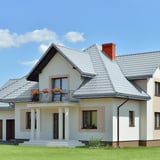 Einfamilienhaus mit Dach aus Pfannenblech Szafir 350/15 in Fehgrau, mit Balkon und Dachrinnen