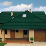 Vorderansicht eines Hauses mit moosgrünem Pfannenblech Szafir 350/15 Dach und Gaubenfenster