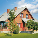 Pfannenblech Szafir 350/15 in Grauweiß RAL 9002 auf einem Ziegelhaus verlegt