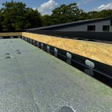 Verlegung des schwarzen EPDM Randfixierstreifens an einer Dachkante mit Befestigungselementen