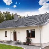 Haus mit Titanzink-Dachrinne und Rinnenablauf, Anwendungsbeispiel mit blauen Himmel