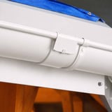 Reinweißer Rinnenverbinder aus Stahl mit Polyurethan-Beschichtung, montiert an einer Dachrinne am Dach
