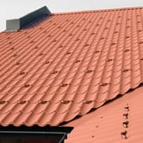 Schneefangbügel Aluminium Ziegelrot auf einem Dach mit Dachpfannenprofilblech montiert, Verlegung