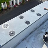 Sechs schwarze EPDM Schrauben Reparaturflicken auf einem Flachdach montiert