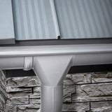 Stahl Dachrinne in Weißaluminium mit Niagara Logo am Ablaufstutzen, montiert unter einem Blechdach