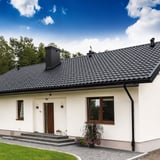 Weisses Haus mit schwarzem Dach und Niagara Stahl Dachrinnen in Tiefschwarz (RAL 9005) komplett montiert