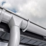 Stahl Dachrinne in Weißaluminium (RAL 9006) mit Wassertropfen, Nahaufnahme des Ablaufstutzens mit Niagara Logo