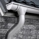 Stahl Dachrinne in Weißaluminium (RAL 9006) mit Fallrohr am Dach eines Hauses montiert